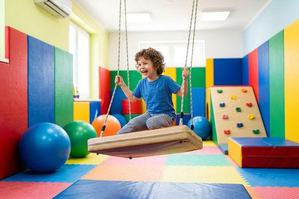 A curious child actively explores colorful sensory equipment inside the CareWorks center sensory room.