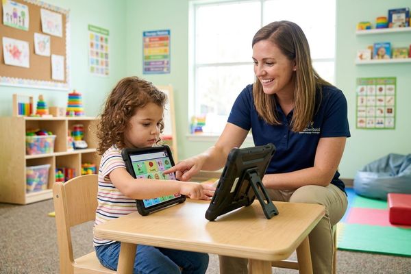 A child learns essential communication skills using a speech tablet device during an ABA therapy session.