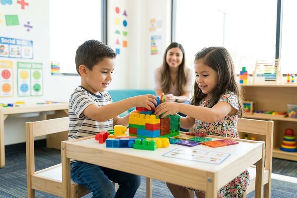 Two young children practice sharing and essential social skills together during a group therapy activity.