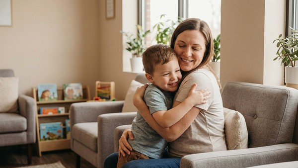 A loving mother warmly hugs her young son while sitting in the waiting room of an ABA therapy center.