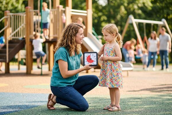 A parent successfully utilizes helpful transition strategies with their child at a sunny local playground.