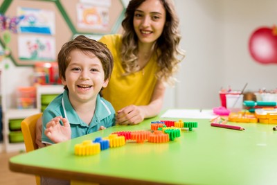 A young child sits engaged at a structured-activity table with their CareWorks therapist during an individualized ABA session.